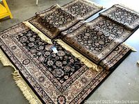 Set of three wool area rugs displayed on floor showing one large rug and two smaller runners all with black background and floral pattern
