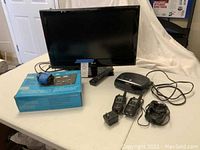 LG 22-inch TV with screen facing forward, includes remote control and other electronics on table