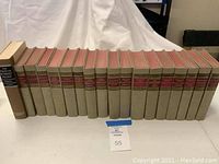 Photo showing full set of 15 classic books arranged horizontally with beige covers and red title bands, including Robert Frost poetry book in slipcase.