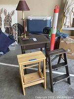 Photo showing small dark wood side table and coordinating lamp, light wood step stool and grey wood step ladder.
