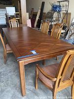 Full view of dining table and chairs showing size, wood finish, and chair upholstery