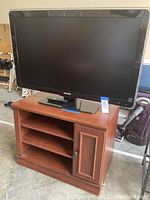 Philips 42-inch TV on top of wooden TV stand showing overall lot view.