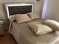 Full view of bed with LED headboard illuminated and mattress dressed in beige quilted cover