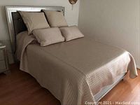 Bed made with queen size bedding set including comforter, sheets, and six pillows in grey and silver.