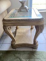 Side view of one Matter Bros end table showing glass top, carved scroll legs, and lower shelf.