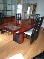 Full view of vintage dining table with six black dining chairs around it, showing high gloss wood surface and placemats on the table.