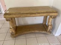 Front view of the wooden entryway table showing the gold finish and carved decorative elements.