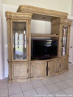 Front angled view of the full five-piece entertainment unit showing wood finish, glass doors, and open TV space.
