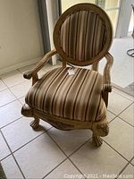 Front and side views of the upholstered armchair with carved wooden frame and striped fabric seat and backrest.