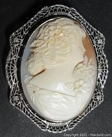 Front view showing oval shell cameo carved with female profile set in openwork filigree 14K white gold frame