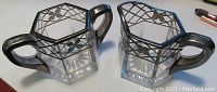 Pair of sterling overlay Heisey glass creamer and sugar bowl showing geometric and floral sterling design on clear glass with starburst base.