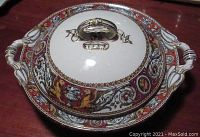 Covered casserole displaying red Florentine pattern with gold accents and central handle on lid.