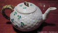 Side view of Belleek tea pot showing basket-weave texture, shamrock hand-painted decoration, and bamboo-style handle.