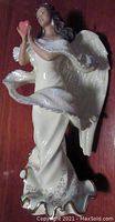 Front side of porcelain Serena Angel of Tranquility figurine showing angel in white gown holding pink heart.