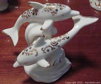Porcelain dolphin figurines showing colorful decorative patterns and gold accents on fins and tails.