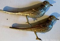 Side view of two bird-shaped silver plated salt and pepper shakers showing detailed body and legs.