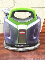 Front view of Bissell LittleGreen ProHeat Pet cleaner showing translucent dual tanks and ergonomic handle.
