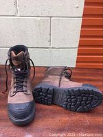Side view of one safety boot standing upright and the other lying on its side showing shape, materials and details.