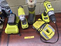 Front view of all tools and chargers on wooden surface against cinder block wall