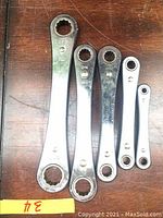 Photo showing the full set of five flat ratcheting wrenches laid out on a wooden surface with size label '3/4' visible next to them.