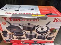 Box showing image and contents of the T-fal Initiatives 20 piece cookware set including fry pans, covered pots, and kitchen tools.