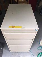 Top view of beige metal filing cabinet showing three drawers and lock area without key