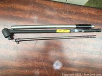 Breaking bar, extension tube and long breaker bar laid out on a wooden surface