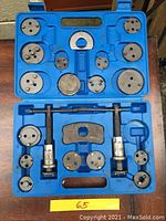 Full blue plastic carrying case with various brake caliper wind back tool adapters and two spring-style caliper tools.