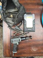 Maximum brand rivet tool with multiple metal attachments beside black carrying bag and Workpro LED light on brown wooden surface