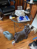 Photo of the Yorkie dog sculpture holding a pinecone, the bunny sculpture, blue glass dolphin figurines on white tray, cookie jar, and appetizer plates on a wood floor.