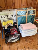 Lot of pet supplies showing crate box, pet gate, pet stairs, dog clothing, grooming tools, and folded blankets