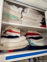 Closet shelf with folded towels in various colors including white, light green, navy blue, and red.