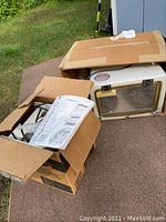 Photo showing open box with GE ice maker installation kit manual and hardware parts, next to sand blaster box.
