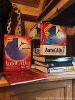Photo of AutoCAD LT 98 and AutoCAD LT 2000i Windows boxed software on a wooden surface with chain in background.