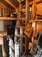 General view of the three ladders stored in a wooden shed, showing the wooden 9-step and 5-step ladders alongside an aluminum multi-purpose ladder.