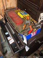 Top down view of a tool drawer and box with assorted tools including screwdrivers, socket wrench case, clamps, and wrenches