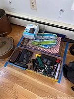 Photo showing lot contents including boxed mosquito repellent, grill basket, tablecloths, and assorted small items.