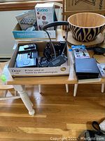Box containing iHome docking station Model IH58 with remote, car power mount Model PUPH, and various cables and accessories on wooden table with other boxes and wooden bowl nearby.
