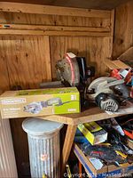 Wood shed corner shelf holding Delta miter saw, Craftsman circular saw and boxed Rockwell compact circular saw