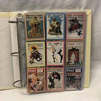 Nine Norman Rockwell trading cards arranged in a 3x3 grid inside a plastic sheet in a binder