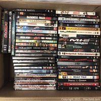 Top view photo showing stacked DVDs with titles like Gladiator, 28 Days Later, The Matrix, Spider-Man and more in a box.