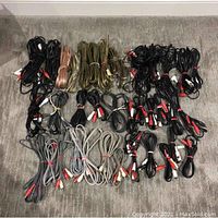 Photo showing a variety of bundled RCA and speaker cables arranged in rows on carpeted floor.