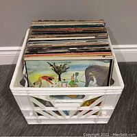 Plastic milk crate containing a stack of approximately 50 vinyl LPs visible from the side