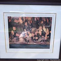 Framed print showing a child sitting by water with reflections in the background, likely the Tom Thompson print titled 'Cedar and Pines'