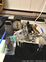 Photo showing full lot with kitchen scale, cheese grater, meat grinder, hand tools, and Ball jars arranged on a surface