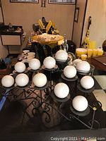White spherical candles displayed on black wrought iron multi-arm candleholders.