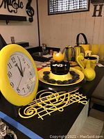 Yellow rim clock with black musical note shaped metal tray and black wrapped chocolates in yellow bowl ice bucket