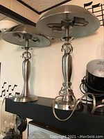 Photo showing pair of brushed metal spotlight table lamps with circular dome shades and decorative ring stem design.