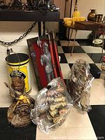 Photo showing the Pittsburgh Pirates trashcan, knight wall art, plastic-wrapped pirate ship models, sailor lamp, and decorative scabbards arranged on floor.