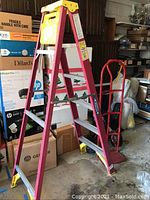 6 foot Werner step ladder and red hand truck dolly shown together in cluttered garage